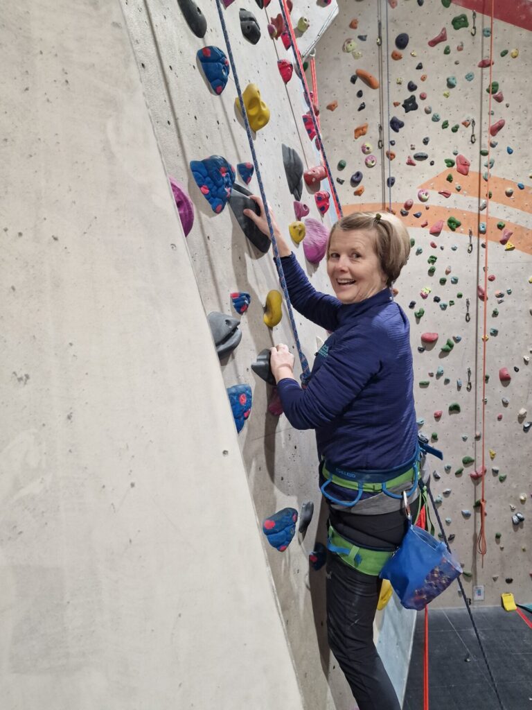 Woman on climbing wall posing for a photo
