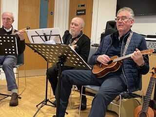 Players playing their instruments seated in front of music stands