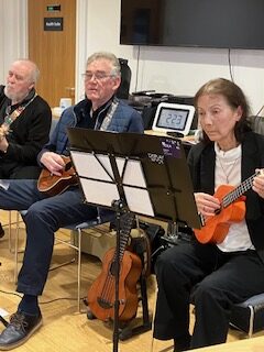 Players playing their instruments seated in front of music stands
