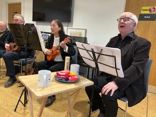 Players playing their instruments seated in front of music stands