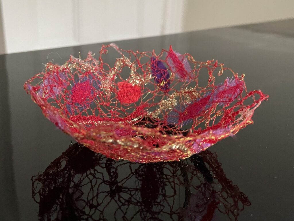 Red, mauve and gold fabric bowl on shiny black surface
