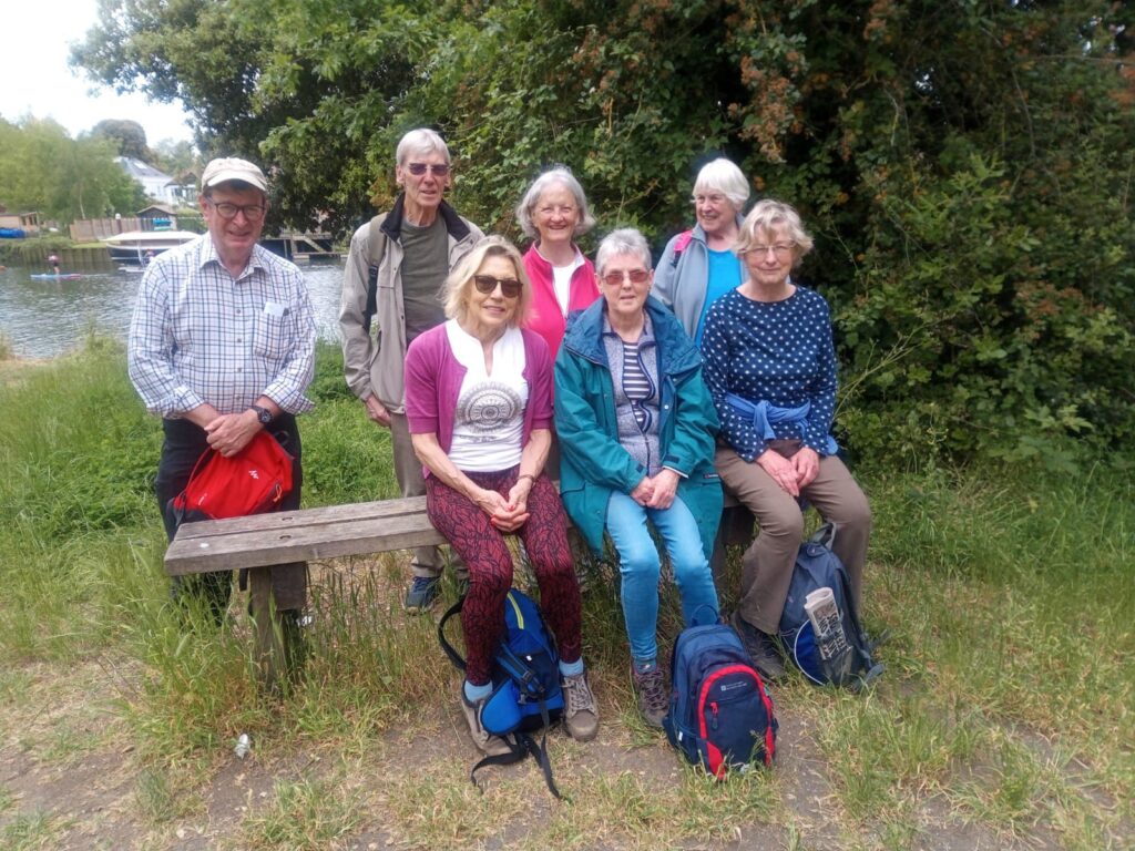 Standing and seated group of walkers posing for photo beside river
