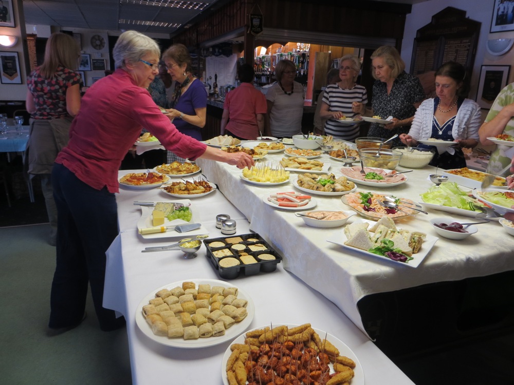 People helping themselves to food on a buffet table