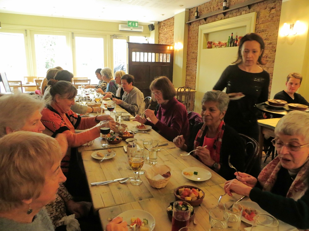 People seated at a table, having a meal in a restaurant with a waitress serving them