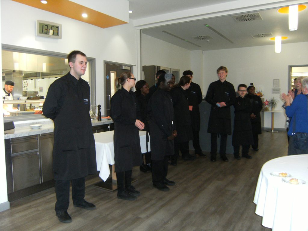 Standing restaurant serving staff dressed in black being applauded