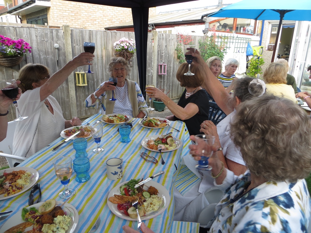 People seated at a table having a meal, raising glasses in a toast